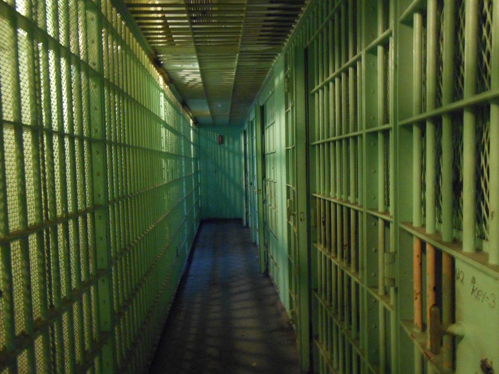 A green jail cell with bars on the walls.