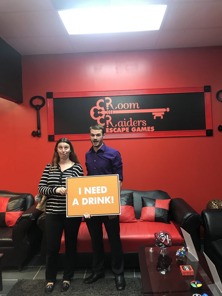A man and woman holding up a sign in front of a red wall.