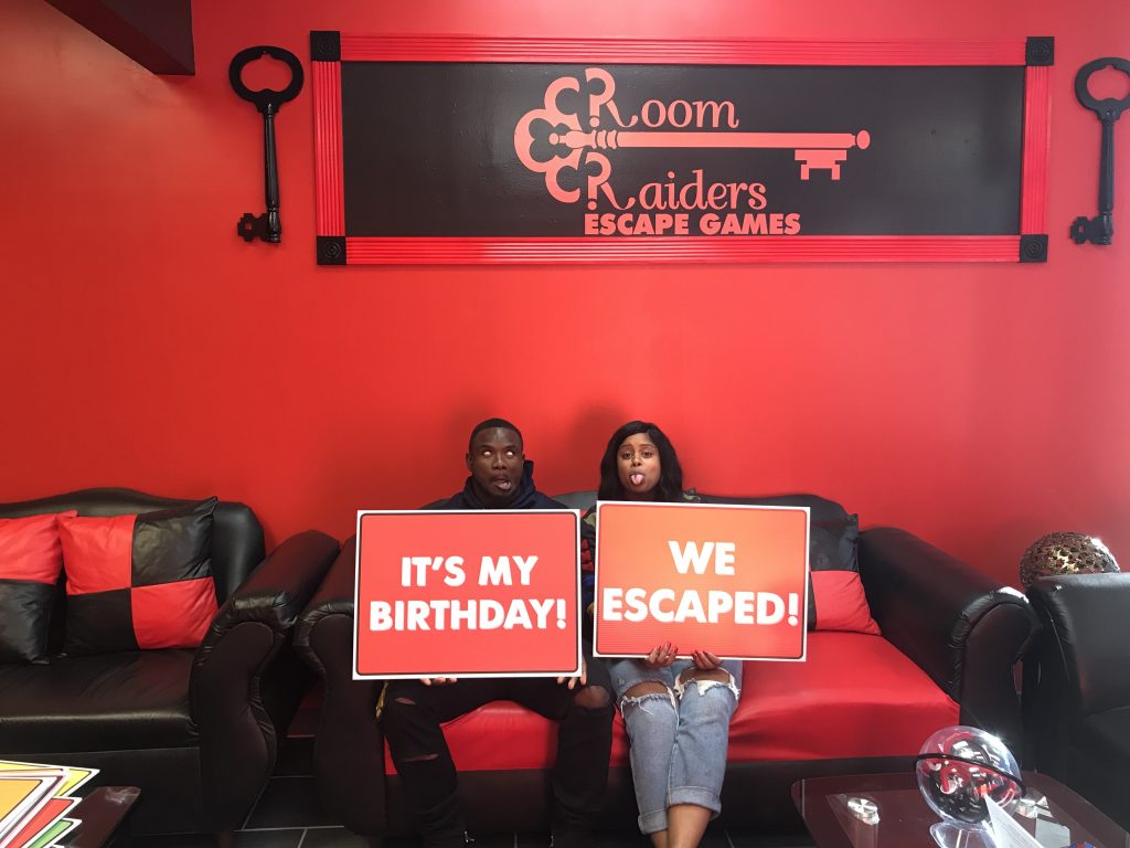 Two women holding signs in a room with red walls.