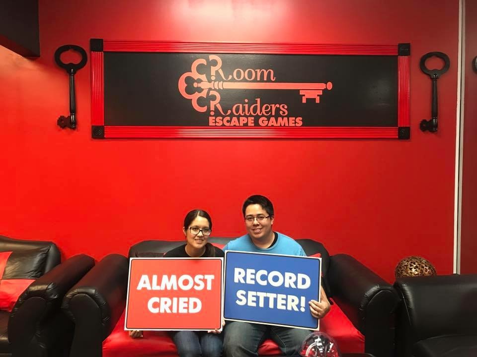 Two people holding signs in front of a red wall.