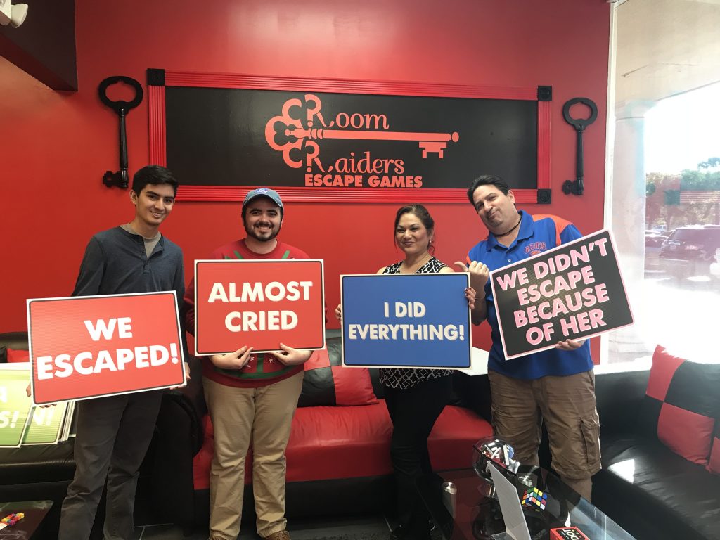 Four people holding signs in front of a red wall.