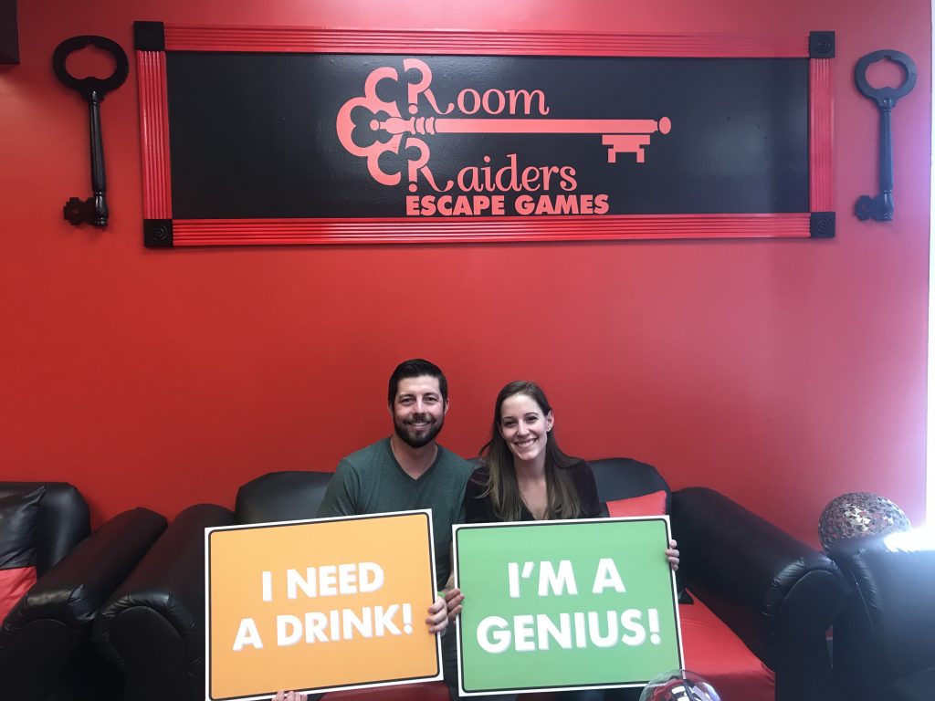 Two people holding signs in a room with a red wall.