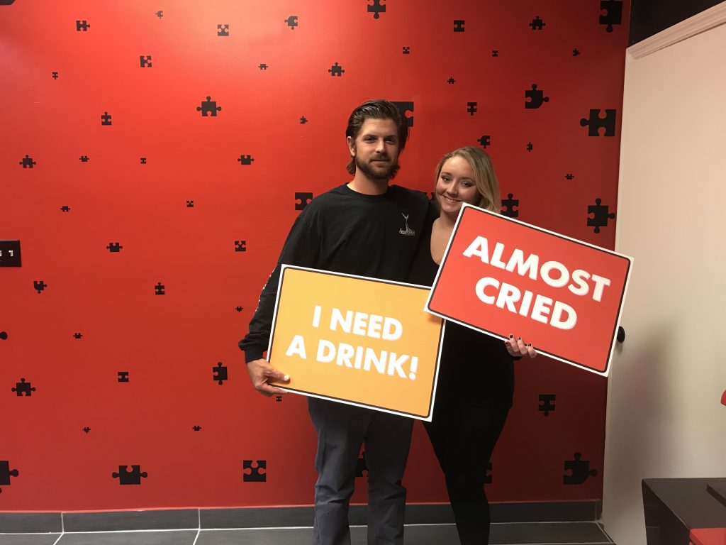 Two people holding signs in front of a wall.