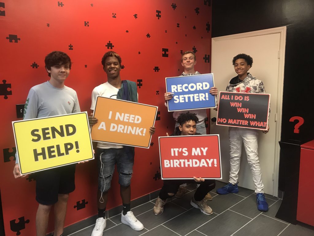 A group of young men holding signs in front of a wall.