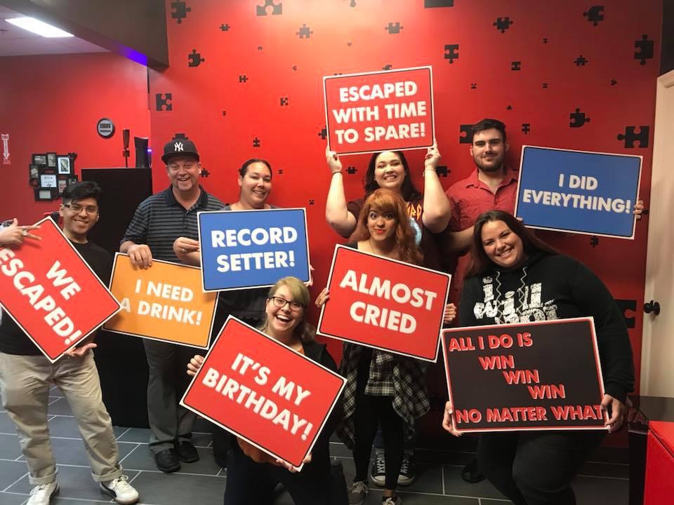 A group of people holding signs in front of a wall.