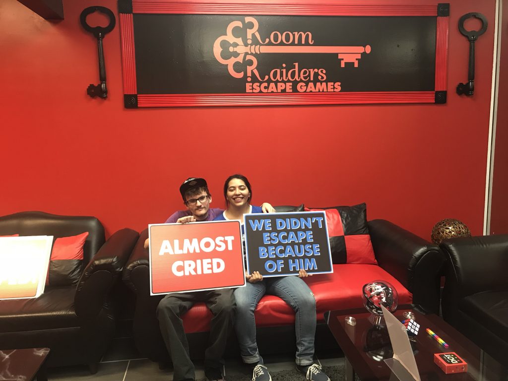 Two people holding signs in a room with red walls.