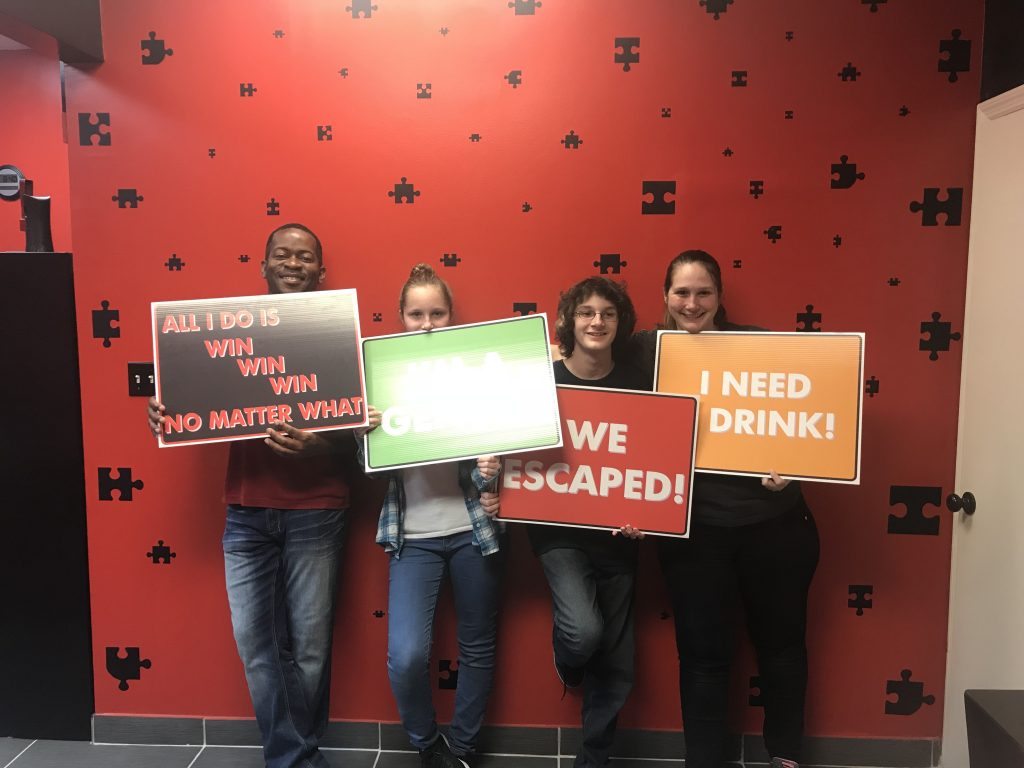 Four people holding signs in front of a wall.