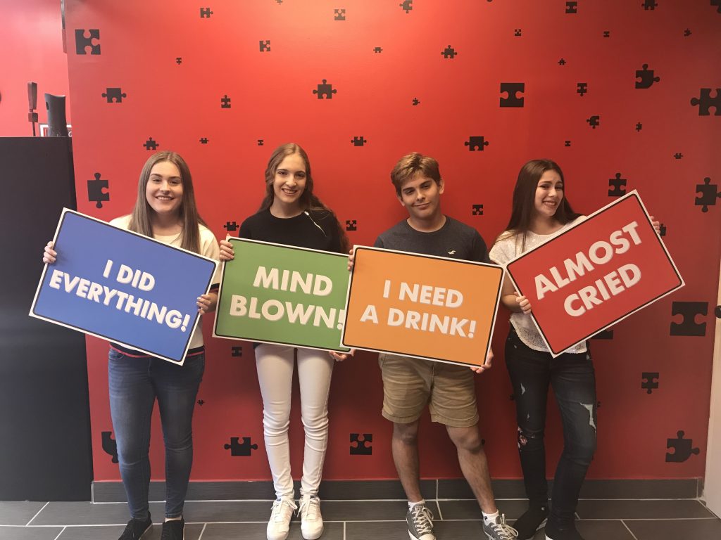 Four people holding up signs in front of a wall.