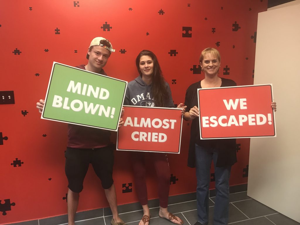 Three people holding signs in front of a wall.