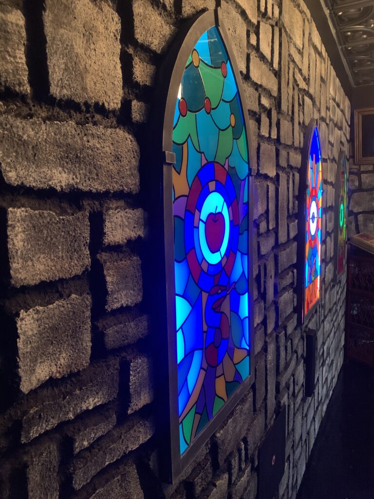 Colorful stained glass windows glowing on a stone wall.
